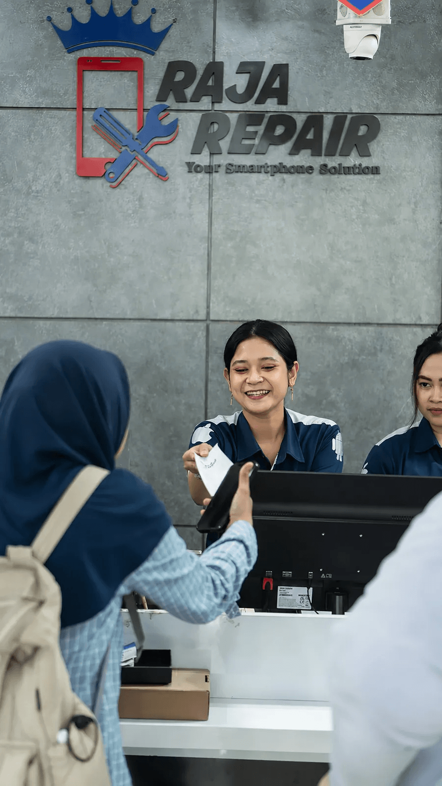 Raja Repair staff serving a customer at the front desk